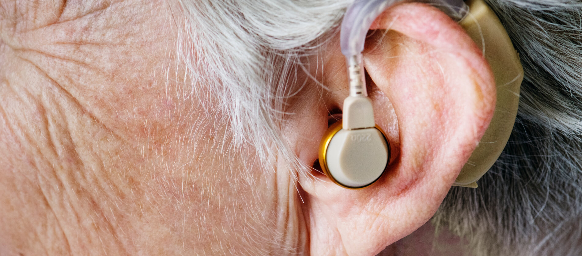 Side profile of an aging person with a hearing aid 