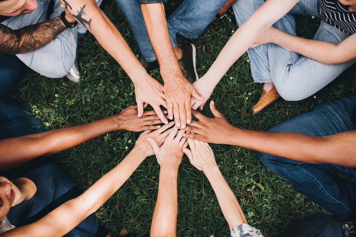 Group of people sitting in a circle and putting their hands in the middle
