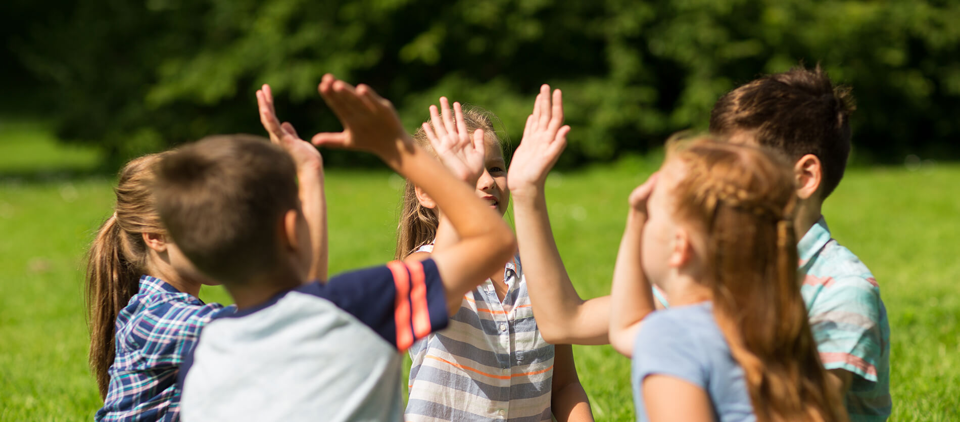 Group of five children high fiving in a circle